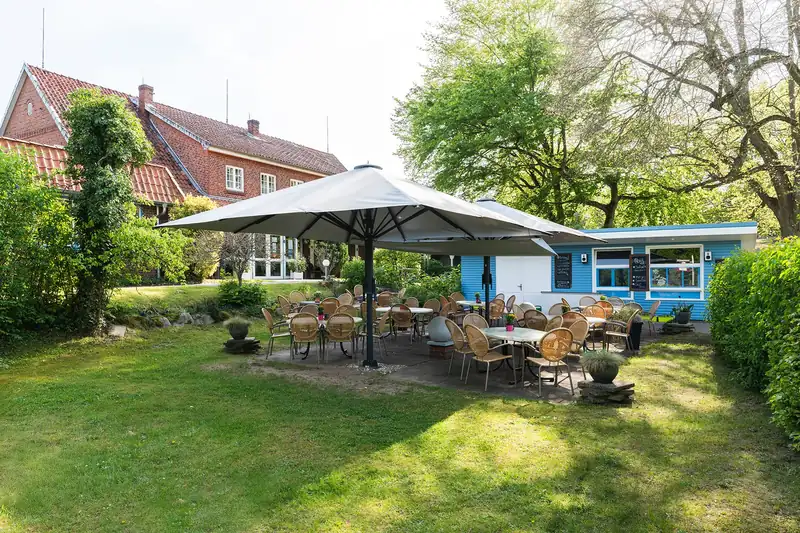 Garten des Hotels mit Sitzplätzen und Sonnenschirm